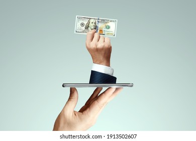 A businessman's hand crawls out of the smartphone screen with a one hundred dollar bill. Concept of money transfers, internet banking work online