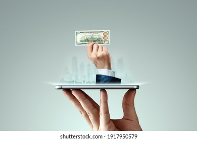 A businessman's hand crawls out of the smartphone screen with a one hundred dollar bill. Concept of money transfers, internet banking work online - Shutterstock ID 1917950579