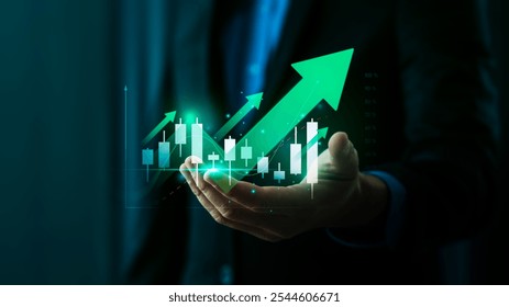 Businessman's Hand Holding Holographic Stock Market Growth Chart with Green Arrow Showing Positive Financial Trends and Stock Candlestick Data on Digital Interface and Finance