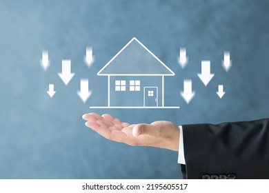 Businessman's hand and house illustration with downward arrows - Shutterstock ID 2195605517
