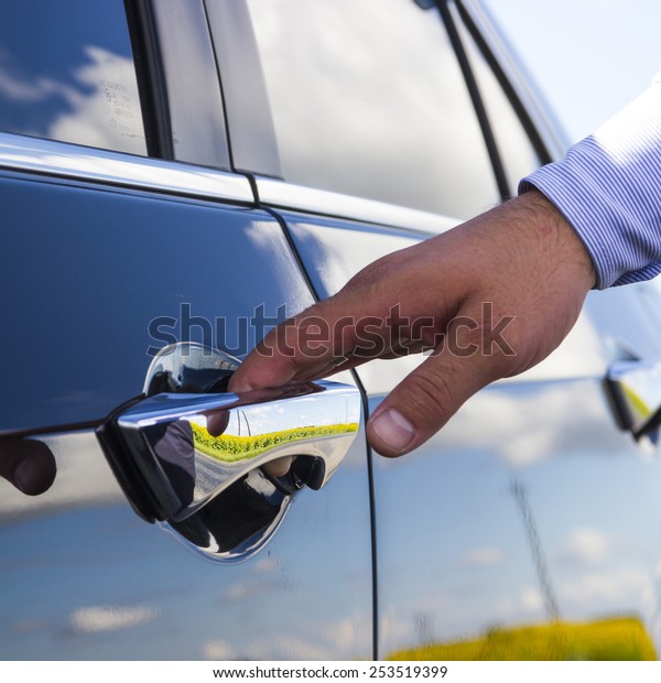 Businessman\'s hand\
opening door of his luxury\
car