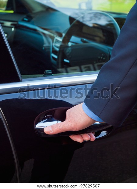 Businessman\'s hand\
opening door of his luxury\
car
