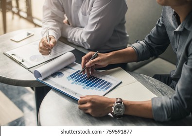 Businessman's hand pointing at business document during discussion at meeting.