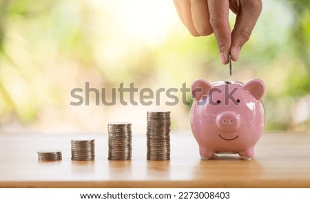 businessman's hand is putting coins on a Pink piggy bank with nature blurred background. a pile of coins, business, investment, finance, and Money Saving for the future concepts