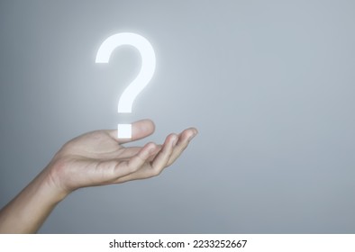 businessman's hand showing a question mark icon. The concept of alternatives. Confusion. Business solution. gray background. copy space - Shutterstock ID 2233252667