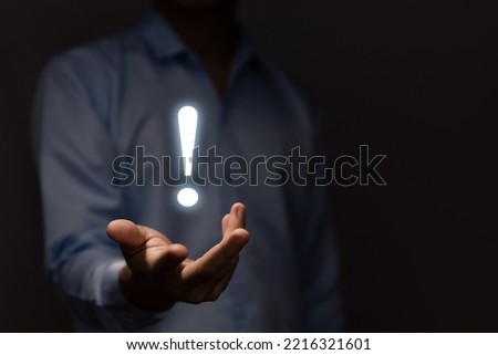 The businessman's hand shows a white exclamation mark. business development concept, error warning, notification, maintenance, and finding a solution. dark background with copy space