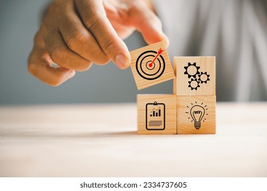 Businessman's hand skillfully arranging wood blocks to illustrate a business strategy and Action plan. This concept emphasizes goal formation and objective achievement. - Shutterstock ID 2334737605