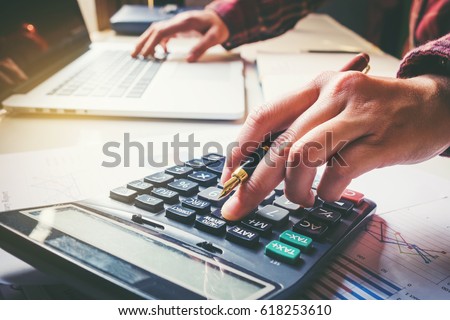 Businessman's hands with calculator at the office and Financial data analyzing counting on wood desk