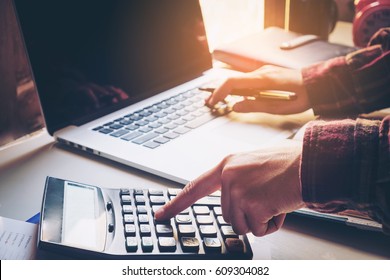 Businessman's Hands With Calculator And Using Laptop At The Office And Financial Data Analyzing Counting On Wood Desk