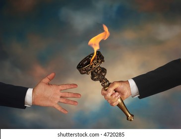 Businessman's Outstretched Arm Passing A Flaming Torch To Another Businessman's Open Hand