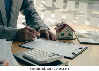 Businessman's Signature On Documents, Checks, And Documents In Real Estate Investment Projects On The Desk. Sales Report On The Mortgage Agent Market In Real Estate Concepts.