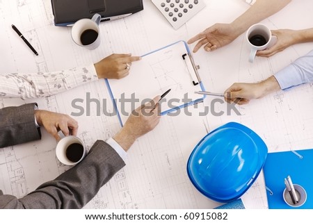 Businessmeeting, closeup hands of architects pointing at clipboard on office table.?