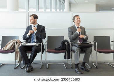 Businessmen adjusting ties in waiting area - Powered by Shutterstock