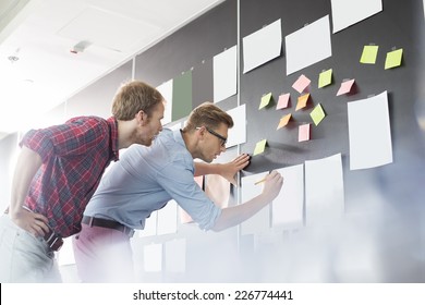 Businessmen analyzing documents on wall in office - Shutterstock ID 226774441