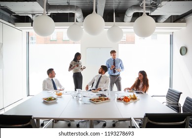 Businessmen And Businesswomen Meeting In Modern Boardroom Over Working Lunch