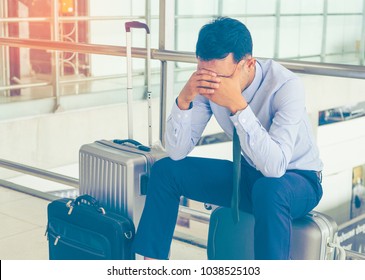 Businessmen are concerned about traveling by plane using your hands closed eyes, unhappy business trip, headache before boarding within the international airport and luggage is placed beside the body.