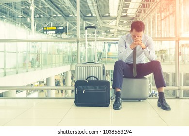 Businessmen are concerned about traveling by plane using your hands closed eyes, unhappy business trip, headache before boarding within the international airport and luggage is placed beside the body.
