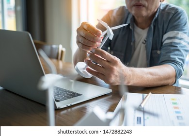 Businessmen Consider The Wind Turbine Model On The Desk, Design And Work In A Laptop.