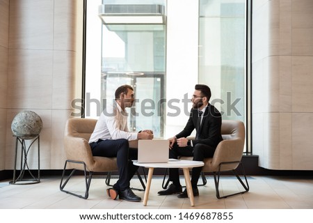 Businessmen discussing deal, sharing startup ideas, business partners negotiations or job interview in modern office with panoramic windows, colleagues talking, working on project together