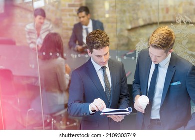 Businessmen Discussing Paperwork Outside Conference Room Meeting