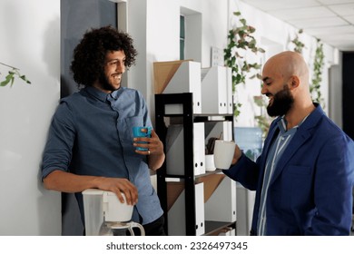 Businessmen enjoying coffee break together and laughing while relaxing in corporate office. Smiling arab young start up company employees mates chatting in coworking space - Powered by Shutterstock