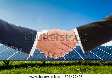 Businessmen handshake on solarpower photovoltaic panel background as bio-energy business team agreement