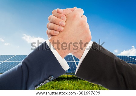 Businessmen handshake as teamwork on solarpower photovoltaic panel background. Renewable energy partnership agreement