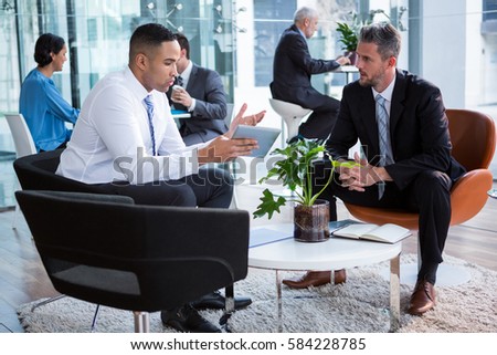 Businessmen having discussion over digital tablet in office