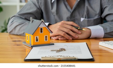 Businessmen holding pens, signing home titles with insurance, care about real estate services and the idea of real estate agents offering interest in installments to their customers. - Shutterstock ID 2155408441