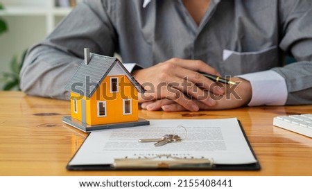 Businessmen holding pens, signing home titles with insurance, care about real estate services and the idea of real estate agents offering interest in installments to their customers.