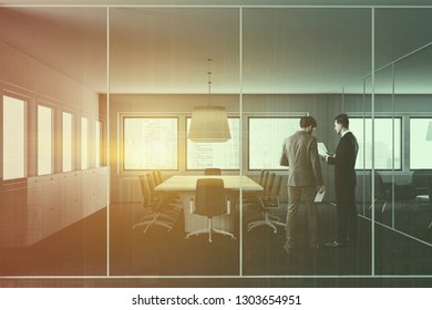 Businessmen in interior of office meeting room with white and glass walls, carpeted floor, long table with gray chairs and row of lockers near the wall. Toned image double exposure