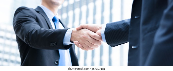 Businessmen making handshake in the city - business etiquette, congratulation, merger and acquisition concepts, panoramic banner