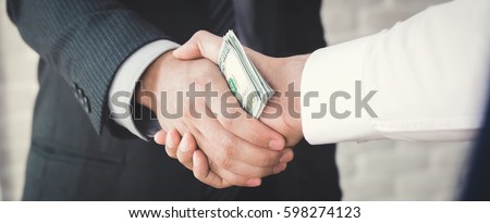 Businessmen making handshake with money in hands - bribery, corruption and venality concepts