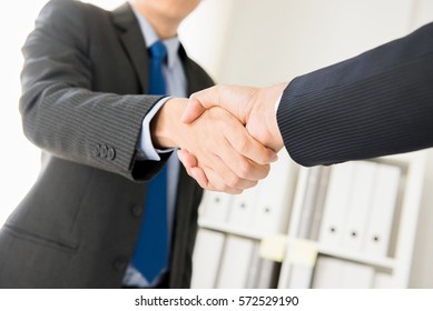 Businessmen making handshake in the office - greeting, dealing, merger and acquisition concepts