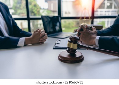 Businessmen And Male Lawyers Or Judges Who Have Team Meetings With Clients. The Concept Of Legal Service Of Injustice With Hammers And Scales Next To It.