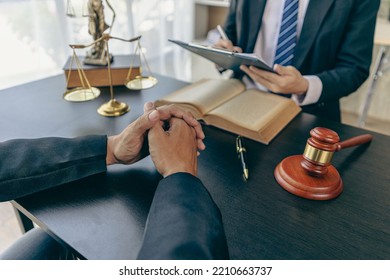 Businessmen And Male Lawyers Or Judges Who Have Team Meetings With Clients. The Concept Of Legal Service Of Injustice With Hammers And Scales Next To It.