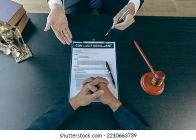 Businessmen And Male Lawyers Or Judges Who Have Team Meetings With Clients. The Concept Of Legal Service Of Injustice With Hammers And Scales Next To It.