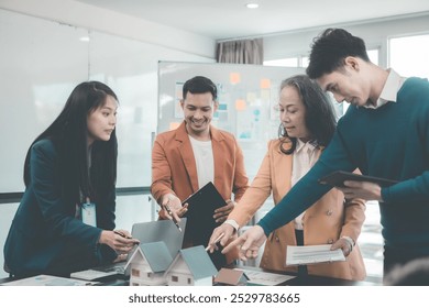 Businessmen are meeting in the office with laptops and architectural models, real estate agent presents house model to young couple and businesswoman in office - Powered by Shutterstock