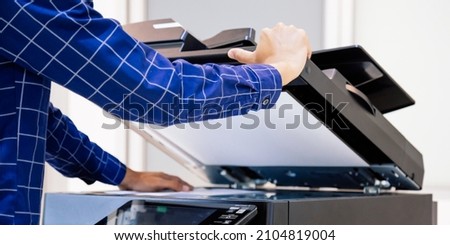 Businessmen press button on the panel for using photocopier or printer for printout and scanning document paper at office.