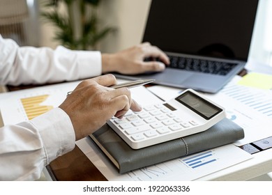 Businessmen press the white calculator to calculate the numbers in the company financial documents, the finance department prepares the document and forwards it to be checked before the meeting.