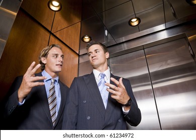 Businessmen riding in elevator conversing - Powered by Shutterstock