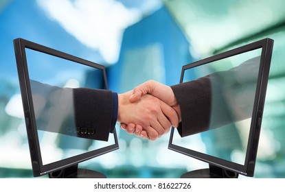 Businessmen shake hands from two lcd monitors