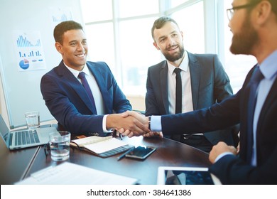 Businessmen shaking hands during a meeting - Powered by Shutterstock