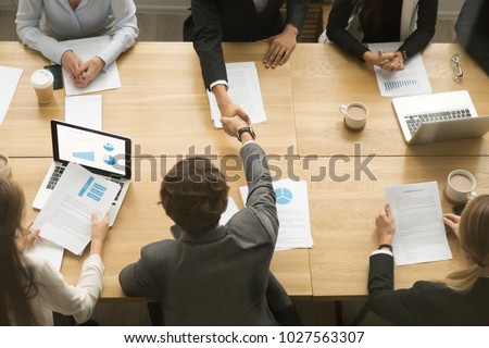 Businessmen shaking hands sitting at conference table during team meeting, two male entrepreneurs handshaking making deal starting collaboration at group negotiations teamwork, top view from above