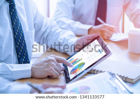 Businessmen tab on tablet touch screen to deeply reviewing a diagram or chart and financial reports for a return on investment or investment risk analysis or business performance.