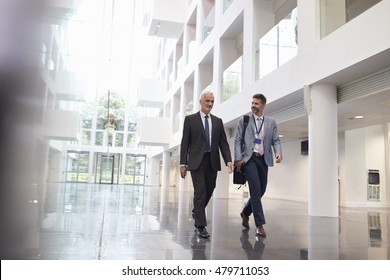 Businessmen Talking As They Walk Through Office Lobby