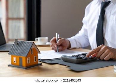 Businessmen Using A Calculator Calculating House Tax Refund On The Table, An Accountant Calculating Tax Report, Financial Concept.