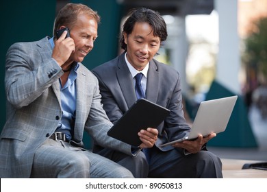 Businessmen Using Laptop And Tablet Pc While Communication On Cell Phone