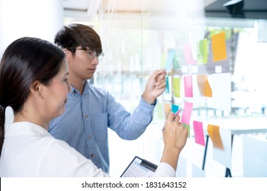 Businessmen and woman are standing He giving advice and brainstorming for Find an ideal and Write to notepad and stick it on the board. - Shutterstock ID 1831643152
