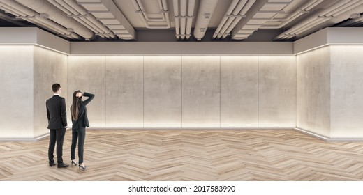 Businessmen And Women Looking At Wall In Modern Exhibition Space Concrete Interior With Mockup Place And Wooden Flooring. Mock Up